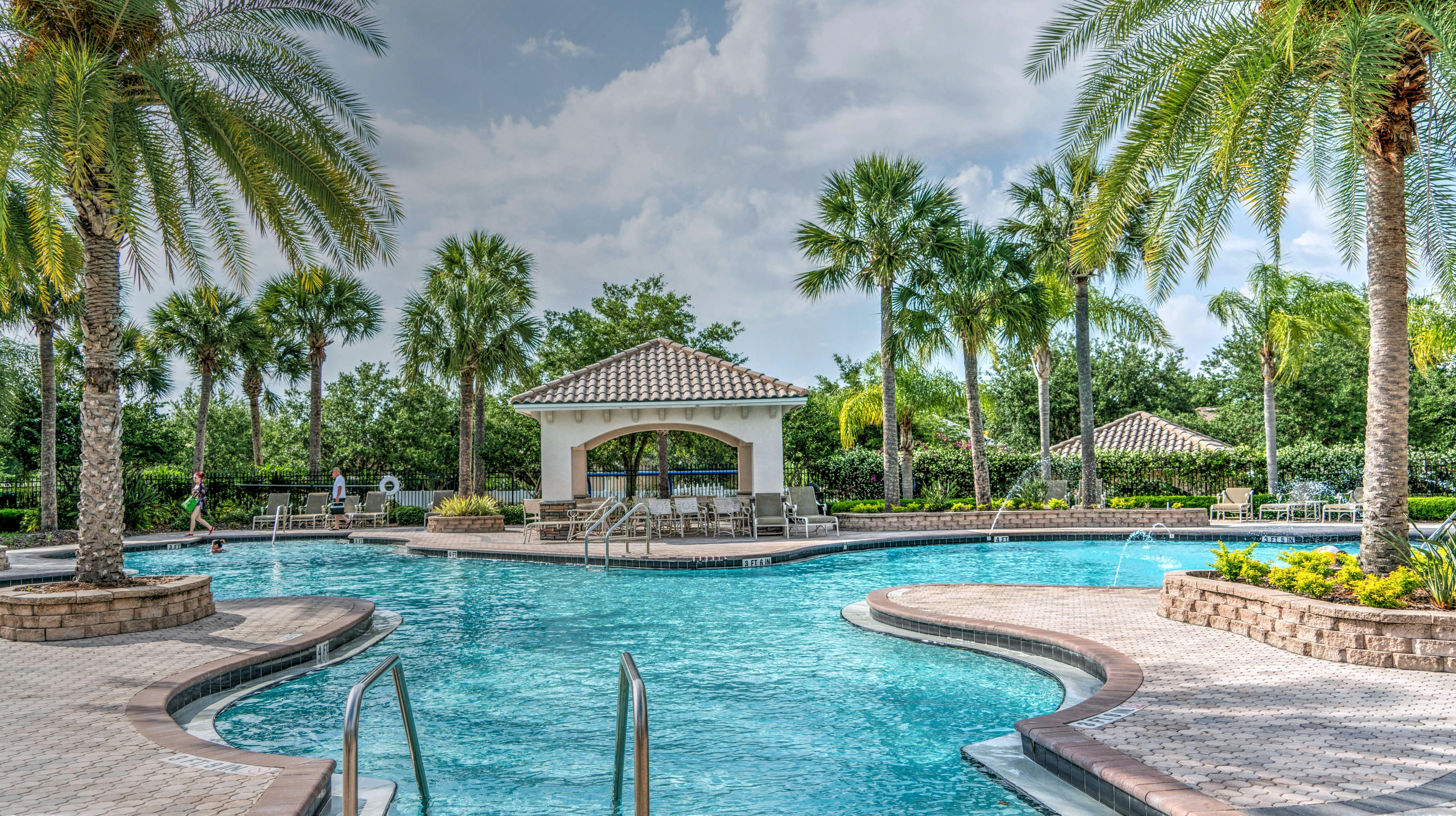 Bright resort-style pool with palm trees and clear blue water
