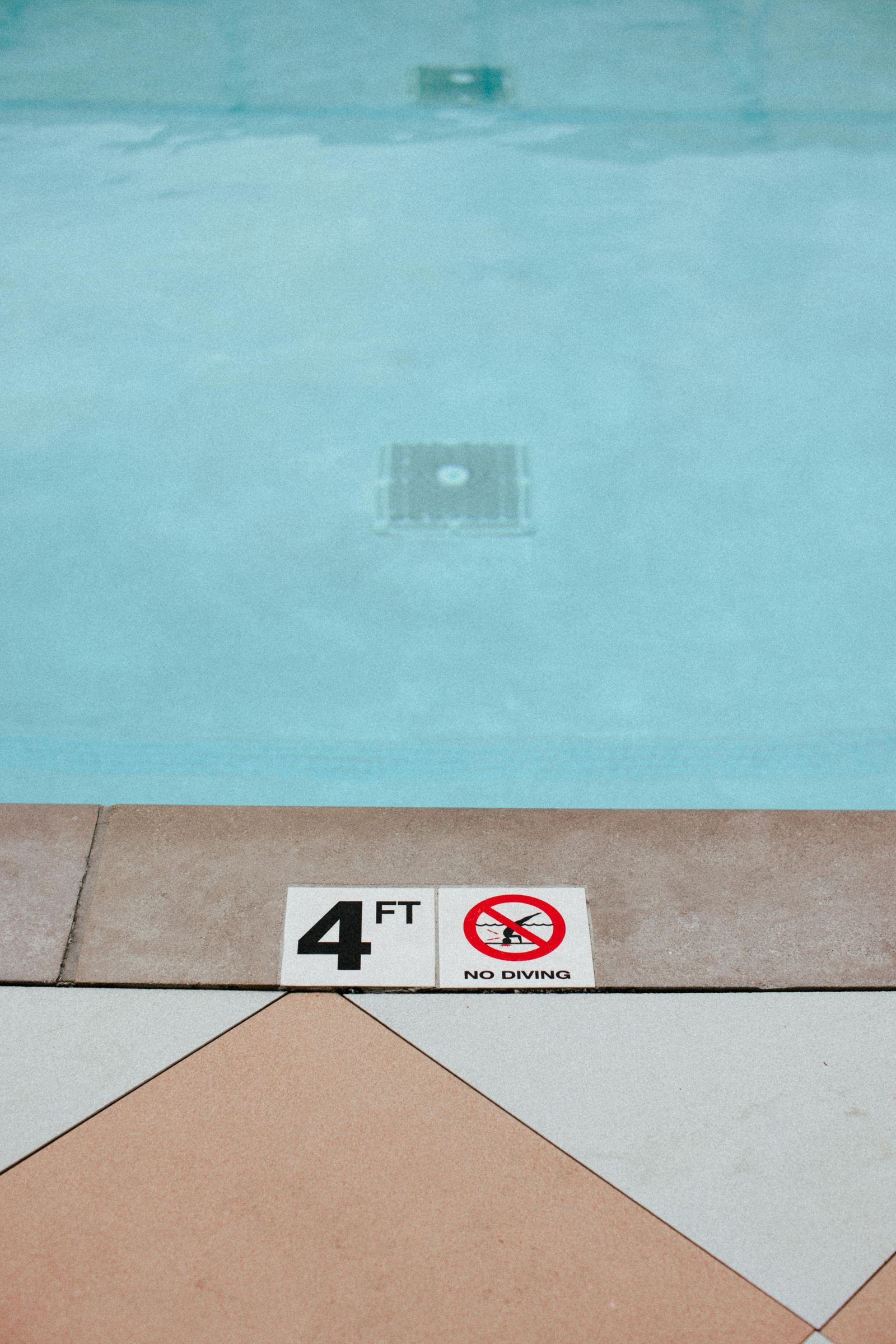 Pool deck depth marker reading 4 FT, No Diving